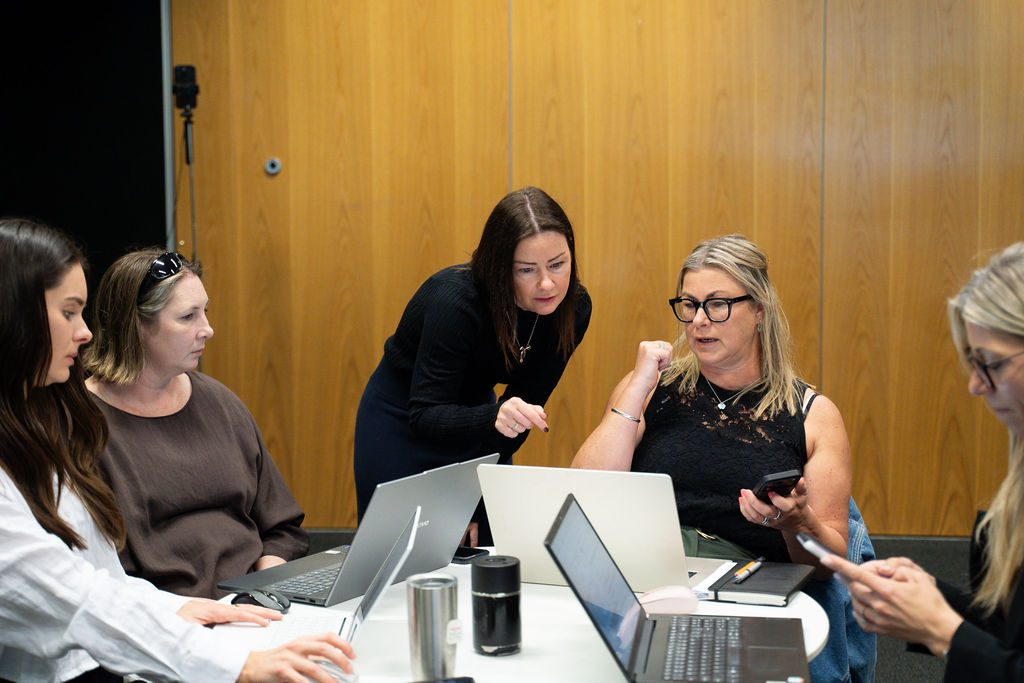 Participants gathered around a laptop working through a problem together